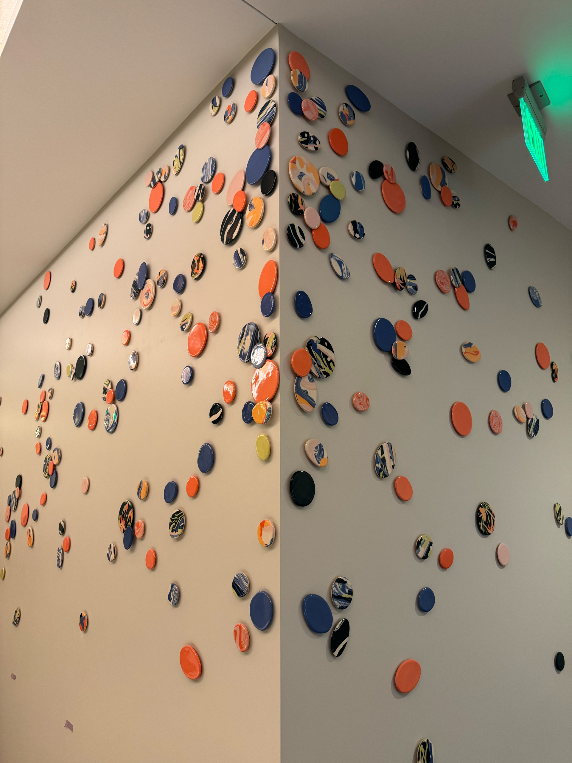 Abstract wall installation of colorful circular tiles wrapping around a corner wall