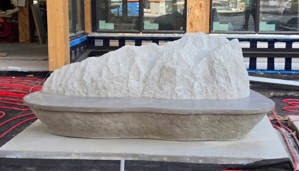 Sculptural bench resembling a carved mountain installed in an outdoor construction setting