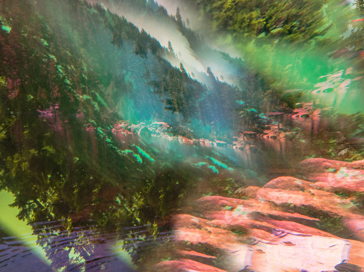 Mountain lake landscape with trees and rocks distorted by colorful light overlays