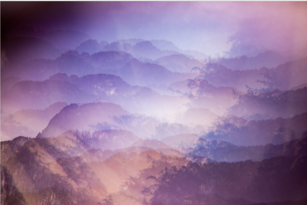 Layered mountain silhouettes in soft purple haze creating atmospheric depth
