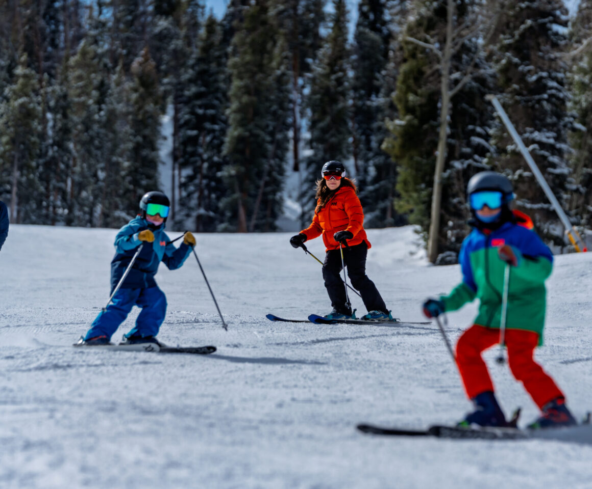 Four people skiing and snowboarding on snowy mountain slope.